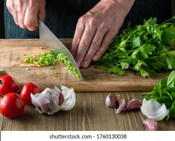 Woman chopping bunch of parsley on a wooden cutting board. - Powered by Shutterstock