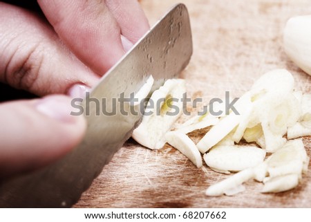 Woman chopping the garlic with knife.