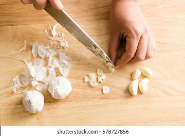 Woman Chopping Garlic On Wooden Board For Cooking