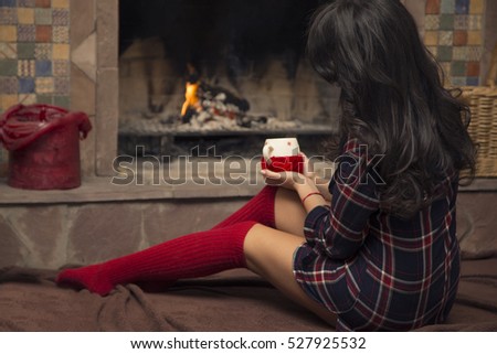 Woman with the Christmas cup by the fireplace