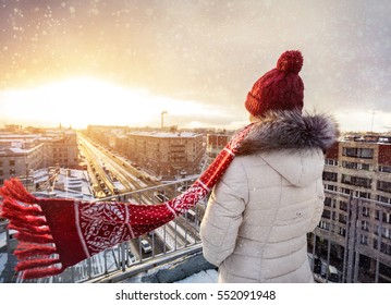 Woman In Christmas Hat And Red Scarf On The Roof At Snow Fall In Saint Petersburg, Russia