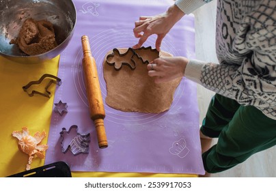 Woman in Christmas sweater making cookies with Christmas shape forms. Rolling pin, gingerbread dough and tangerine on the table. Christmas eve, top view. Pastry preparation. Homemade dessert. - Powered by Shutterstock