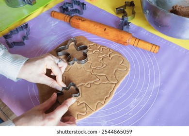 Woman in Christmas sweater making gingerbread cookies in different forms at domestic kitchen. Rolling pin and cookies form at the table with woman chef. Preparing homemade cookies. Christmas time. - Powered by Shutterstock