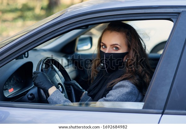 Woman in the city. Person in a mask. Coronavirus\
theme. Woman by the car.