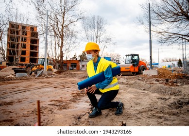 Woman Civil Engineer Holding Injured Knee In Pain, Kneeling At Construction Site On Rainy Bad Weather Day