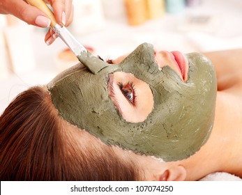 Woman With Clay Facial Mask In Beauty Spa.