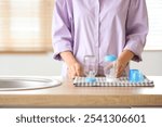 Woman with clean baby bottles at wooden table in kitchen