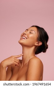 Woman With Clean And Clear Skin Smiling. Female Model With Eyes Closed Against Pink Background.