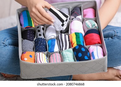 Woman with clean clothes in organizer at home, closeup