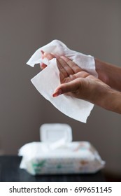 Woman clean hands with wet wipes, package in background - Shutterstock ID 699651145