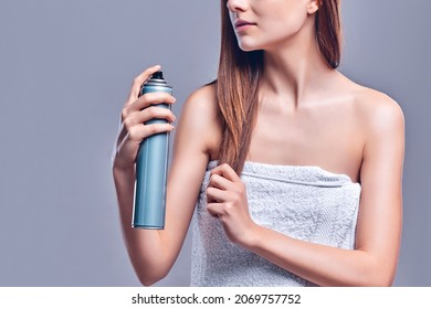 Woman With Clean Radiant Skin In A Towel Uses Hairspray Isolated On Gray Background.