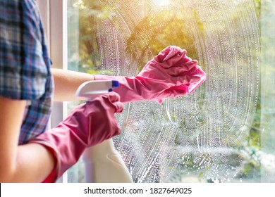 A Woman Clean A Window Pane With A Rag And Soap Suds. Cleaning With A Detergent. Hands In Pink Protective Gloves Washing Glass On The Windows Of The House With A Spray Bottle, Home Routine Concept.