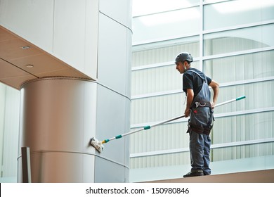 woman cleaner worker in uniform cleaning indoor window of business building