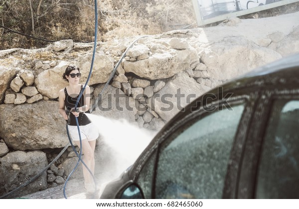 Woman cleaning\
black car with pressurized\
water