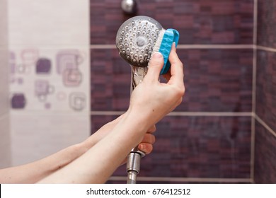 Woman Cleaning An Calcified Shower Head In Domestic Bathroom With Small Brush.