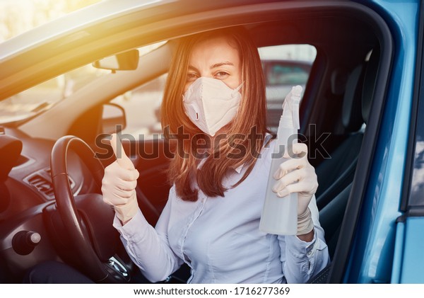 Woman cleaning car with a disinfection spray\
and shows thumb up gesture. Car\
washing