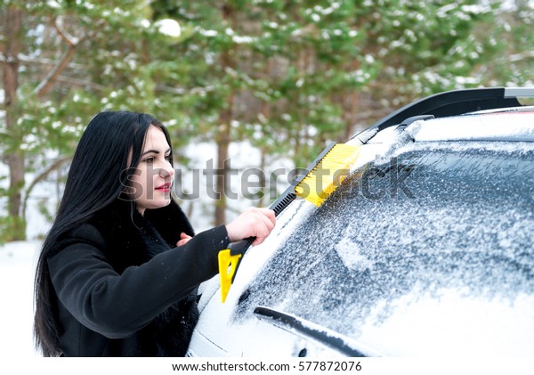 Woman cleaning car windshield of snow winter
happy young scraper