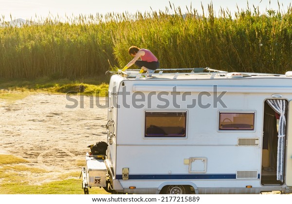 Woman\
cleaning caravan roof. Traveling with motor\
home