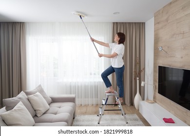 Frauenreinigung Decken mit einem Mopp. Hausfrau reinigt Wohnzimmer