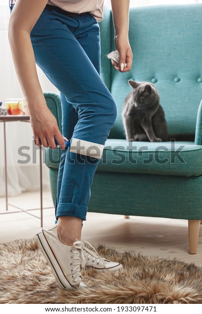 Woman cleaning clothes with sticky roller from\
cats hair, cleaning hair from\
pets