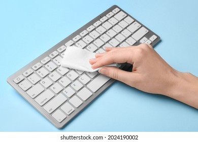 Woman Cleaning Computer Keyboard On Color Background