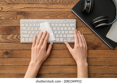 Woman Cleaning Computer Keyboard On Wooden Background