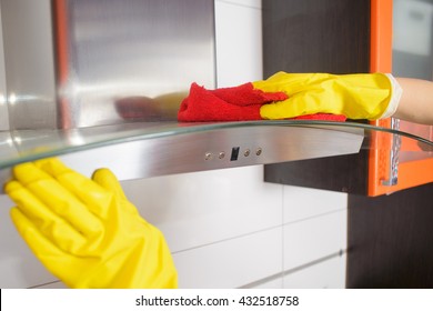 a Woman Cleaning Cooker Hood With sponge In Kitchen At Home
