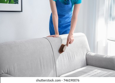 Woman Cleaning Couch With Brush At Home