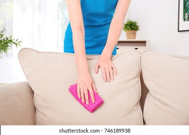 Woman Cleaning Couch With Duster At Home