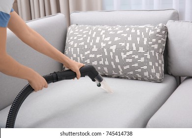 Woman Cleaning Couch With Vacuum Cleaner At Home