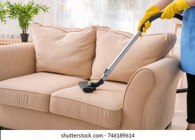 Woman Cleaning Couch With Vacuum Cleaner At Home