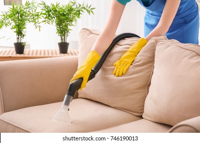 Woman Cleaning Couch With Vacuum Cleaner At Home