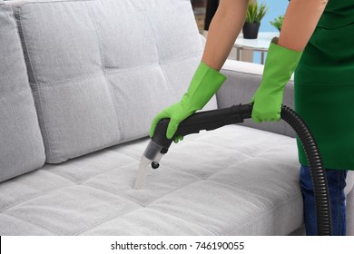 Woman Cleaning Couch With Vacuum Cleaner At Home