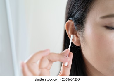 woman cleaning ear with cotton swab. Healthcare and ear cleaning concept - Shutterstock ID 2068654250