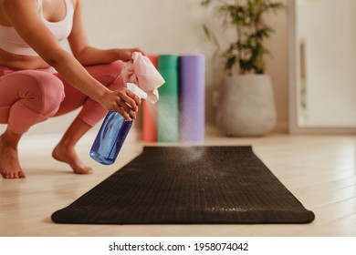 Woman Cleaning Exercise Mat With Disinfectant Spray In Gym. Female Sanitizing Fitness Mat With Disinfectant Spray At Home.