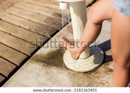 Woman cleaning feet in a shower after beach day. Beach hygiene. Close up