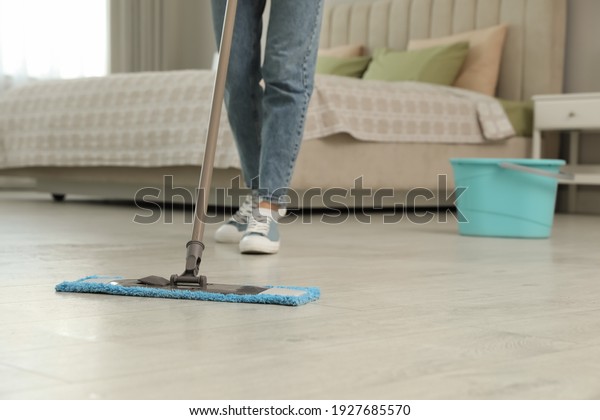 Woman cleaning\
floor with mop at home,\
closeup