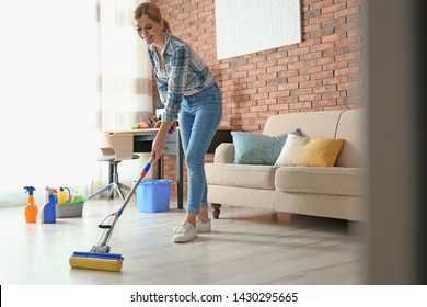 Woman cleaning floor with mop in living room - Powered by Shutterstock