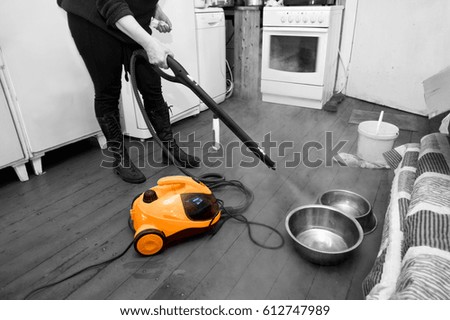 Woman cleaning floor with steam or hot water spray,  kitchen interior. Selective color shot