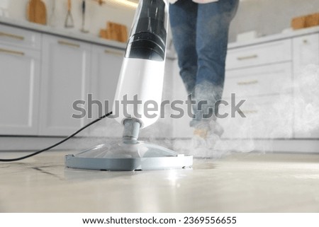 Woman cleaning floor with steam mop in kitchen at home, closeup 商業照片 © 
