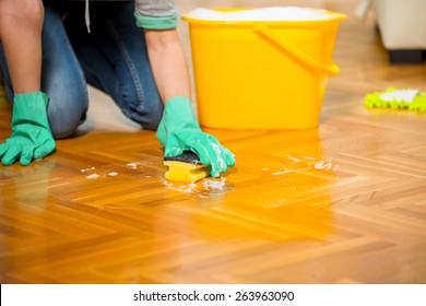 Woman cleaning the floor while kneeling at home