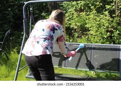 Woman Cleaning Garden Furniture And Getting The Garden Ready For Summer