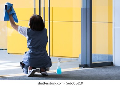 A Woman Cleaning A Glass Door.