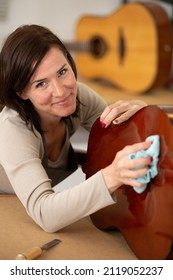 Woman Cleaning Guitar In Guitar Maker Workshop