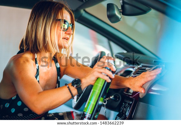 Woman
cleaning her car cockpit using spray and microfiber cloth to clean
and shine dashboard at self service car wash
garage