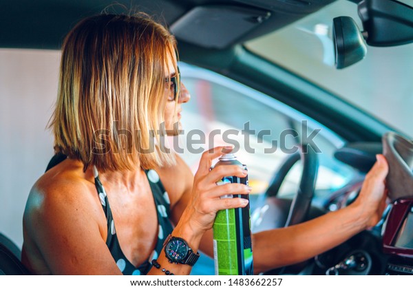 Woman\
cleaning her car cockpit using spray and microfiber cloth to clean\
and shine dashboard at self service car wash\
garage