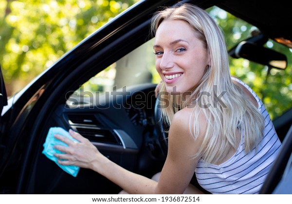 woman cleaning her car cockpit using spray and
microfiber cloth
