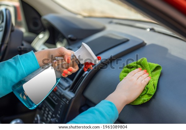 woman cleaning\
her car cockpit using spray and microfiber cloth. blank white label\
on a spray bottle. copy\
space