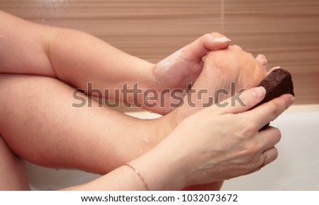 Woman cleaning her feets by pumice in bath 