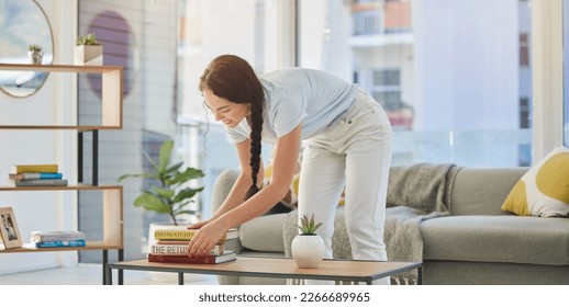 Woman, cleaning and house with books in lounge, table and organize for housekeeping, tidy and order. Happy cleaner girl, book stack and living room for clean home, neat apartment or flat in New York - Shutterstock ID 2266689965